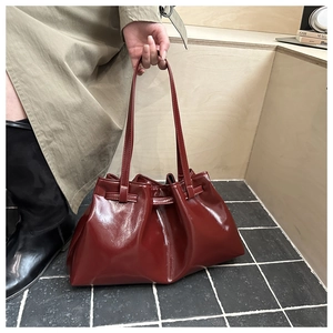 Detail of dark red pleated glossy patent leather handbag with large capacity design