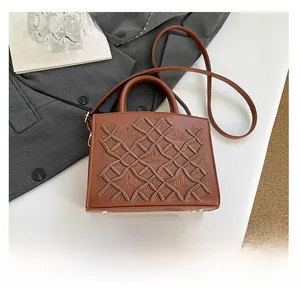 Detail view of brown embroidered lady bag with woven texture next to a smartphone