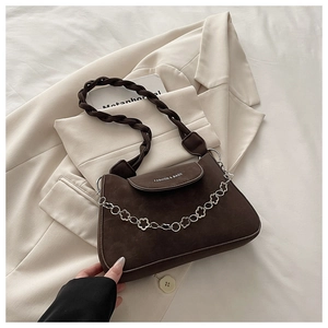Detail of dark brown matte shoulder bag with woven handle and silver flower chain