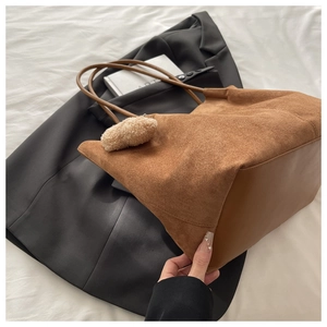 Gros plan d'un sac cabas en daim marron avec détail de charme pompon en peluche chic