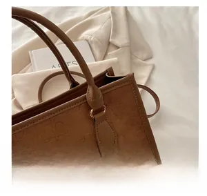 Dettaglio borsa tote in pelle scamosciata marrone con trifoglio goffrato e fibbie