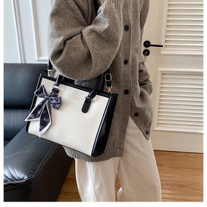 Détail du sac cabas blanc gaufré serpent avec bordure noire et nœud en foulard de soie