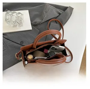 Top view of large brown patent tote bag interior with smartphone and cosmetics inside