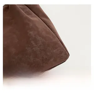 Gros plan sur la texture en daim marron foncé et les coutures soignées d'un sac cabas