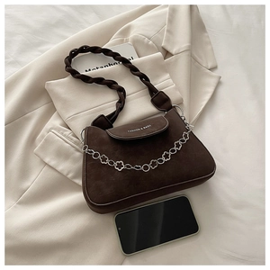 Detail of dark brown matte leather bag with silver floral chain and woven strap