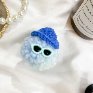 Detail of cute plush doll phone grip with blue knit hat and sunglasses on silk