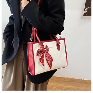 Detail of a contrast color tote bag featuring snake pattern and decorative red silk scarf