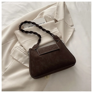 Detail of a dark brown crossbody bag with a thick braided strap on a white blazer