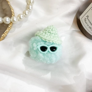 Detailed view of mint green crochet doll phone grip with sunglasses on white fabric
