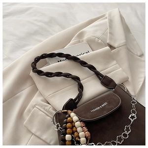 Detail of dark brown matte leather bag with woven strap and beaded floral chain