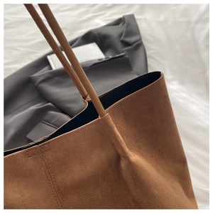 Gros plan d'un cabas en daim marron avec coutures précises et texture mate élégante
