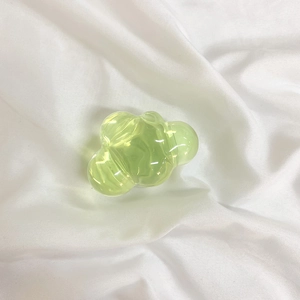 Close-up of a translucent light green cloud-shaped resin phone socket on white fabric