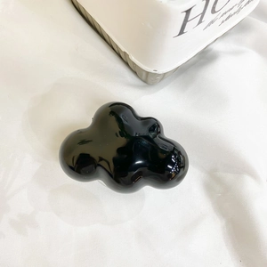 Close-up of a black glossy cloud-shaped phone socket on a white textured background