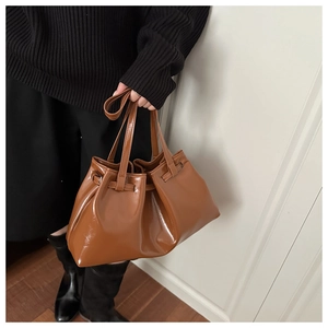 Detail of caramel brown faux leather tote with drawstring closure and ruched pleats