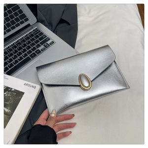 Detailed view of silver Saffiano leather clutch with golden oval metal lock and flap