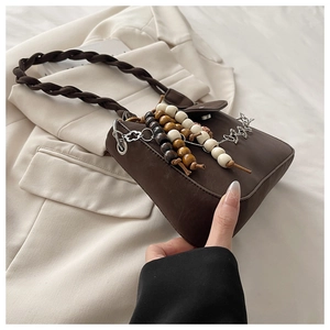 Close-up of vintage brown bag with braided handle and decorative wooden beads