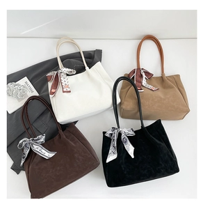 Gros plan de quatre sacs cabas en daim de différentes couleurs avec des foulards en soie décoratifs