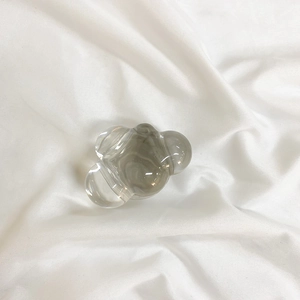 Top view of smoke gray cloud-shaped phone grip on a white wrinkled fabric background