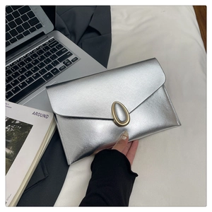 Close-up of silver envelope clutch bag with cross-grain texture and oval gold buckle detail