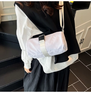 Detail of white cylinder travel bag with nylon texture and black buckle on a modern model