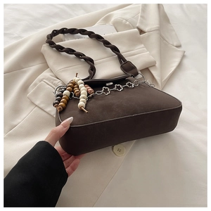 Detail of dark brown faux leather bag with chunky woven strap and floral metal chain