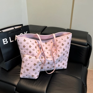 Pink PU leather tote bag with brown pegasus print and matching small pouch on a black sofa
