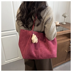 Détail du grand sac cabas en daim bordeaux avec un charm étoile en peluche jaune
