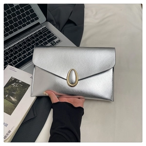 Detailed view of silver envelope clutch bag with crosshatch texture and gold buckle
