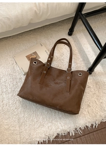 Detailed overhead shot of a vintage brown tote bag with metal eyelets on a rug