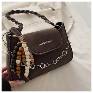 Detail of dark brown leather handbag with woven handle, wooden beads, and floral chain