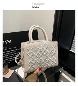 Detailed view of white patent leather tote featuring geometric quilted texture and silk scarf