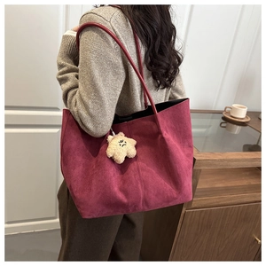 Détail du sac cabas en daim bordeaux avec breloque étoile en peluche porté par un mannequin