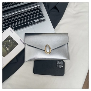 Close-up of silver envelope clutch with fine cross pattern and gold oval metal buckle