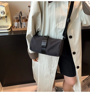Close-up of black nylon crossbody bag with adjustable strap and large buckle on a model