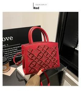 Detail of red embroidered lady handbag featuring structured top handle and stylish texture