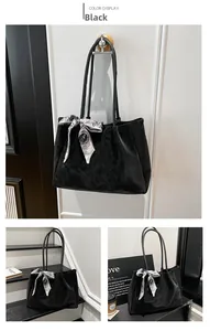 Detail of a black matte tote bag with an elegant floral scarf and slim top handles