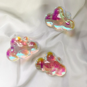 Macro shot of colorful iridescent cloud charms on white silk fabric with light reflections
