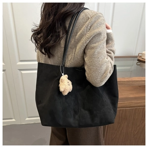 Détail de la texture du sac cabas en daim noir avec un petit pendentif ours peluche