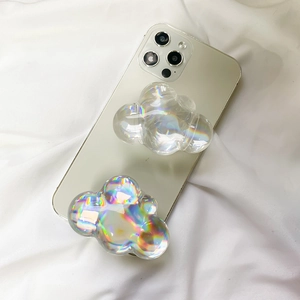 Close-up of cloud-shaped iridescent laser phone grip holders on a white fabric background