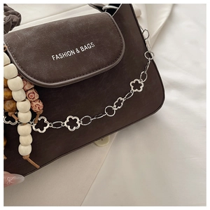 Detail view of dark brown suede bag with silver flower chain and floral bead charms
