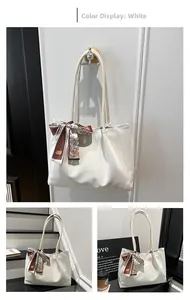 Detailed view of a white suede tote bag with a decorative brown patterned silk scarf accessory