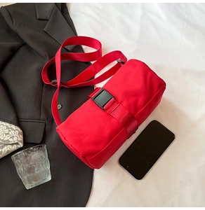 Detailed view of red waterproof nylon cylinder travel bag with black plastic buckle strap
