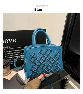Detail of blue quilted handbag with embossed pattern and golden hardware accents