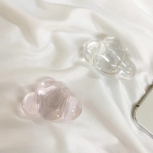 Close-up of translucent cloud-shaped resin phone grips on elegant white satin fabric