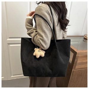 Détail du grand sac cabas en daim noir avec pendentif étoile sur l'épaule du modèle
