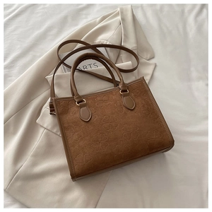 Dettaglio della borsa tote marrone con motivo a trifoglio in rilievo e texture opaca