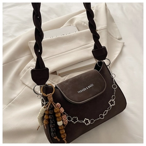 Detail of dark brown shoulder bag with woven strap and decorative flower chain