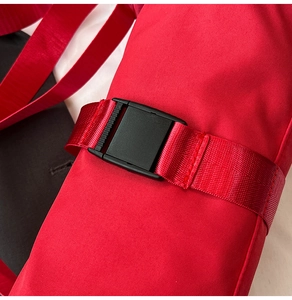 Detailed macro shot of a durable black buckle and red nylon strap for travel bags