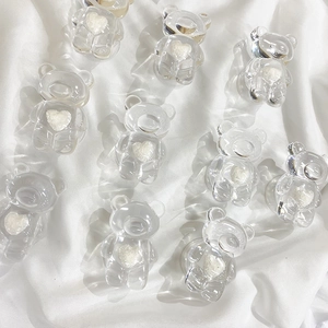 Transparent resin bear phone grips with white glitter hearts on clean white fabric background
