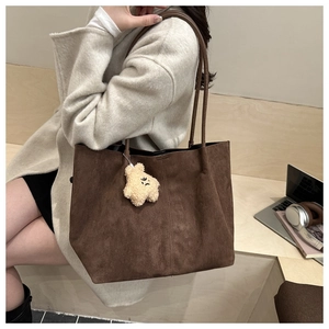 Sac cabas en daim marron sur un banc avec ordinateur pour une scène de bureau chic